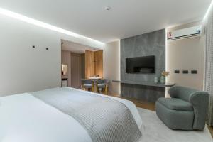 a bedroom with a bed and a chair and a television at Batel Luxury - Próx Pátio Batel in Curitiba