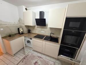 a kitchen with white cabinets and a sink and a dishwasher at Downtown in Bonn