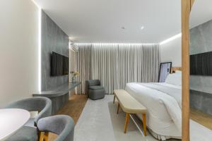 a hotel room with a large bed and chairs at Batel Luxury - Próx Pátio Batel in Curitiba