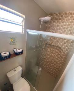 a bathroom with a toilet and a glass shower at Casa Amarela Milagres in São Miguel dos Milagres
