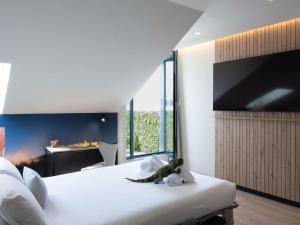 um quarto com uma grande cama branca e uma televisão na parede em ibis Styles Santander em Santander