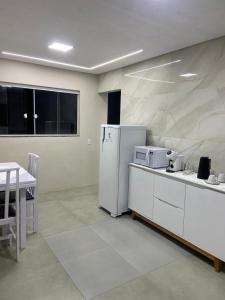 una cucina con un frigorifero bianco e un tavolo di Recanto do Sol a Governador Celso Ramos