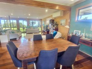 a living room with a wooden table and blue chairs at Vista at Straddie View in Dunwich