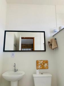 a bathroom with a mirror above a toilet and a sink at Suítes Cabanas Coral in Serra +30 photos