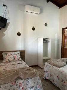 a bedroom with two beds and a tv on the wall at Pousada Estância Mineira in Guapé