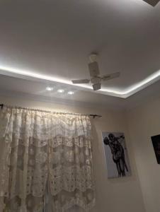 - un ventilateur de plafond dans une chambre avec rideau dans l'établissement Ocean Breeze Apartments zanzibar, à Zanzibar City