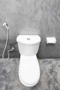 La salle de bains est pourvue de toilettes blanches et d'un tuyau. dans l'établissement Ocean Breeze Apartments zanzibar, à Zanzibar City