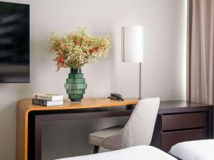 a vase of flowers on a desk with a chair at Novotel Bordeaux Mérignac in Mérignac +248 photos
