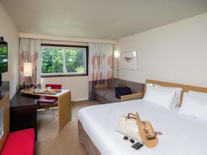 une chambre d'hôtel avec un grand lit et un canapé dans l'établissement Novotel Nantes Carquefou, à Carquefou