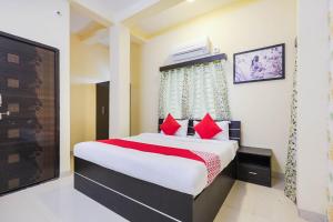 a bedroom with a large bed with red pillows at Hotel O The Dreams in Indore +20 photos