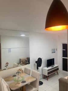 a living room with a dining table and a television at Descanse perto do aeroporto e Conheça Maceió - 24h in Maceió