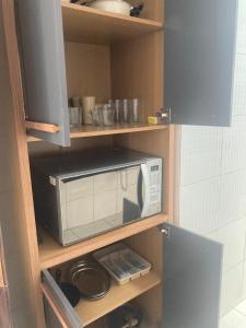 une cuisine avec un four micro-ondes sur une étagère dans l'établissement Descanse perto do aeroporto e Conheça Maceió - 24h, à Maceió 28 autres photos