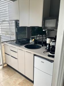 a white kitchen with a sink and a microwave at La perle marine in Le Diamant