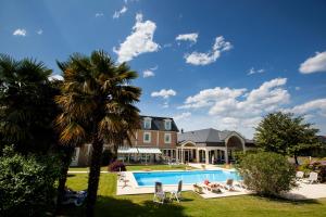 a house with a swimming pool and palm trees at Alysson Hôtel in Oloron-Sainte-Marie