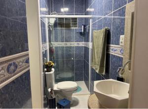 a blue tiled bathroom with a toilet and a sink at Lar dos Fernandes in Belém +6 photos