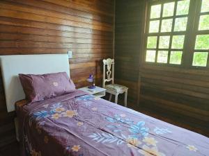 1 Schlafzimmer mit einem Bett mit einer lila Decke und 2 Fenstern in der Unterkunft Recanto Don Ciro in Uruguaiana