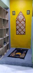 a room with a yellow wall with a rug on the floor at Homestay Permata Cirebon in Ciperna