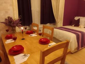 a dining room table with red plates and a candle at Executive Suite at Ideal home & cottage, Inviting 2 Bedroom apartment, Sleep 6 Ideal for contractors, family & Groups in Birmingham +7 photos