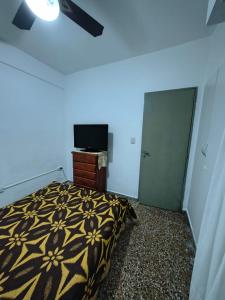 サンベルナルドにあるDepto 2 amb San Bernardoのベッドルーム(ベッド1台、テレビ、ドア付)