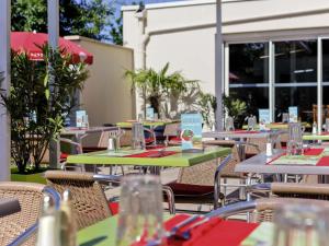 un patio al aire libre con mesas, sillas y ventanas en ibis Lyon Est Bron, en Bron