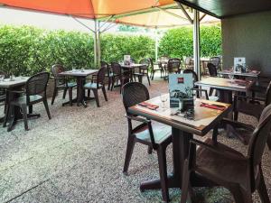 an empty restaurant with tables and chairs and umbrellas at ibis Montbéliard in Montbéliard