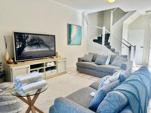 een woonkamer met een blauwe bank en een tv bij 3 Yaringa in Port Douglas
