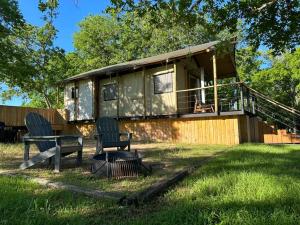 een huis met twee stoelen in het gras bij Premium Lakefront Cabin 4 The Cardinal in Bastrop