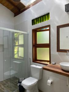 um banheiro com vaso sanitário, pia e janela em Loft 95m Sea - Private - condominium em Ilhabela