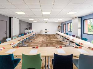 une grande salle de conférence avec de longues tables et chaises dans l'établissement Ibis Lyon Villefranche Sur Saone, à Limas