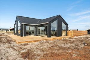a house with a black roof and a wooden deck at 382-Harboore-Charlottevej-6 in Harboør