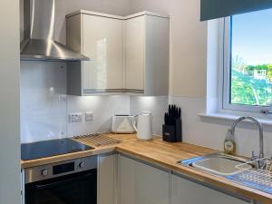 a kitchen with white cabinets and a sink and a window at The Narrows in Poolewe +6 photos