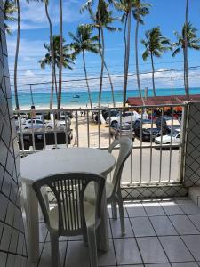 a table and chairs on a balcony overlooking the beach at Casa de praia inteira pé na areia Maragogi in Maragogi