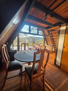 a dining room with a table and chairs and a window at Cabana Fé Miguel Pereira Com Ofuro e Por do Sol in Miguel Pereira