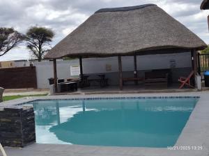 a large swimming pool with a thatch roof at Precious Guest House in Manamakgoteng