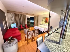 a living room with a red couch and a bedroom at Kubitschek Plaza Hotel - Flat Particular 4 - ALM Hospedagens in Brasília