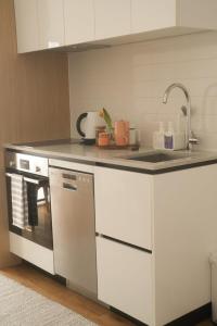 een witte keuken met een spoelbak en een vaatwasser bij The Urban Nest in Wellington +13 foto's