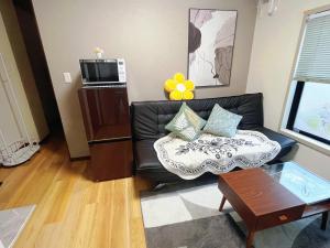 a living room with a black leather couch and a table at 子安居3nd専用#3部屋6ベッド in Yokohama