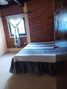 a bedroom with a bed with a brick wall and a window at Casa de descanso Emiliano in Salta
