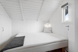 ein weißes Bett in einem kleinen Zimmer mit Fenster in der Unterkunft 0206 Rømø - P S Carlsvej 22 in Tagholm