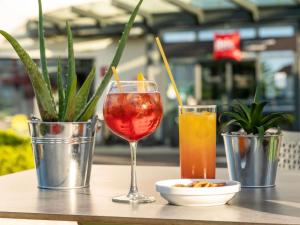 a table with two cocktails and a plate of food at ibis Clermont Ferrand Montferrand in Clermont-Ferrand