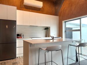 a kitchen with white cabinets and a counter with stools at The Black Shed Studio in New Plymouth