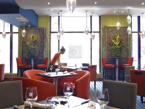 a restaurant with tables and chairs and a man in the background at Novotel Montreal Center in Montréal