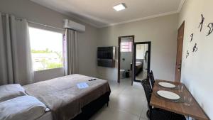 a bedroom with a bed and a table and a television at Apartamento novo próximo a Av do CPA in Cuiabá