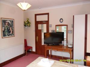 a living room with a tv and a table with a television at Thorpe Lodge Hotel in Peterborough