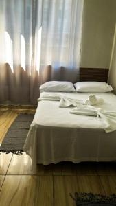 un lit blanc dans une chambre avec une fenêtre dans l'établissement Hotel Colombo, à São Lourenço 4 autres photos