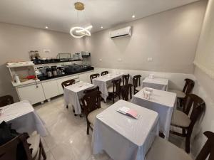 a restaurant with white tables and chairs and a kitchen at Hotel New Space in Sao Paulo