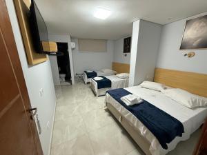 a bedroom with two beds and a flat screen tv at Hotel New Space in Sao Paulo