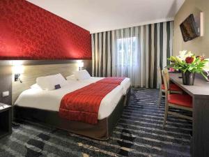 a hotel room with a large bed and a desk at Mercure Rouen Val de Reuil in Val de Reuil