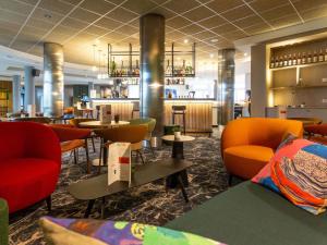 a restaurant with chairs and tables and a bar at Novotel Bourges in Bourges