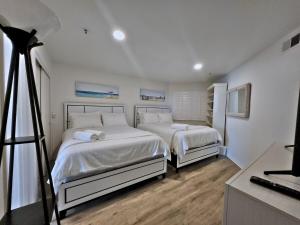 two beds in a white bedroom with a camera at Modern Coastal Escape Breathtaking Ocean in Imperial Beach +23 photos